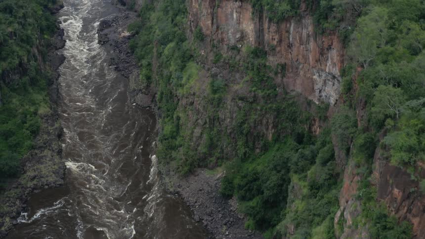 River flows rapidly between forest topped cliffs