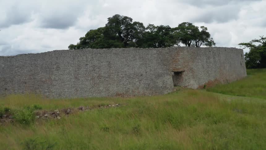 Ancient stone wall ruins in tall grass landscape