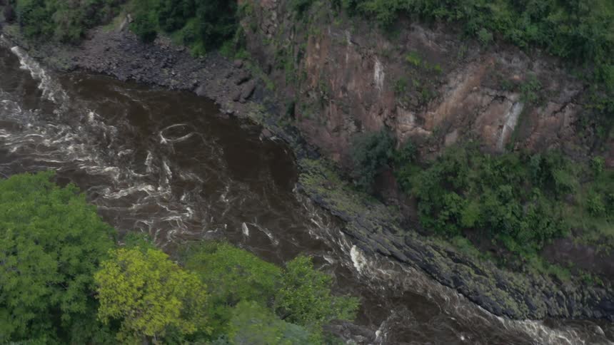 River flows in canyon below forest covered cliffs