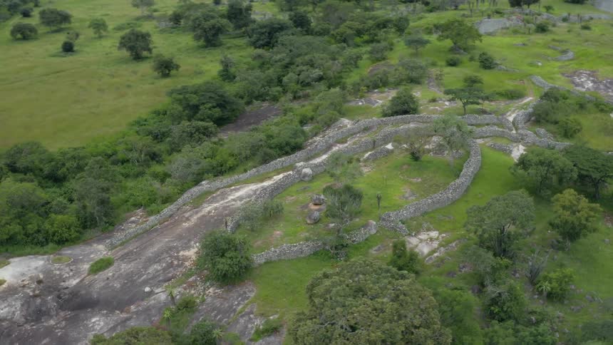 Series of stone walls wrap around hill near forest