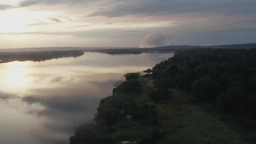 Aerial view of the setting sun reflecting on the calm surface of a river