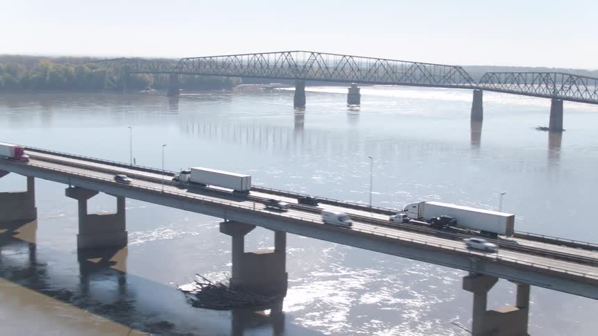 Multiple vehicles are driving on a bridge over a body of water