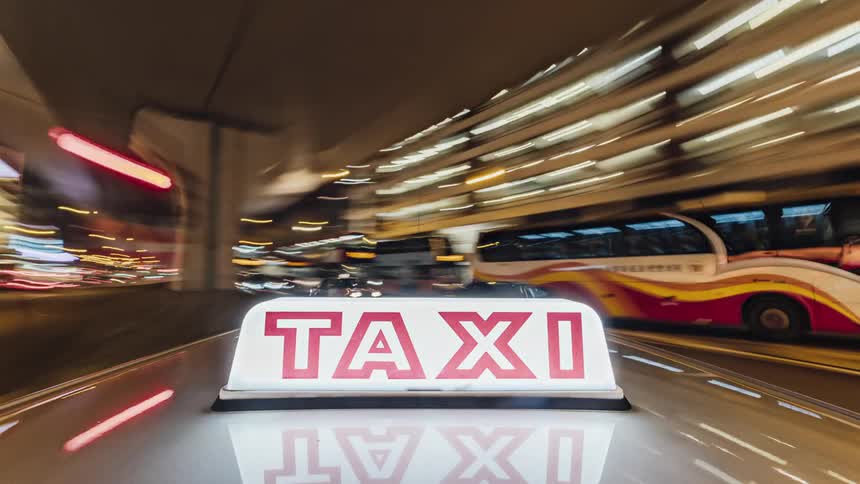 A taxi moving through a crowded busy asian city at night