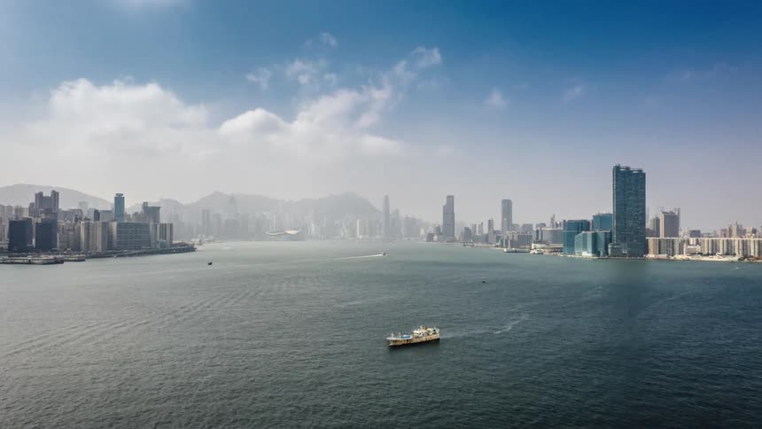 Boats and ships travel on sea with city skyline in the background