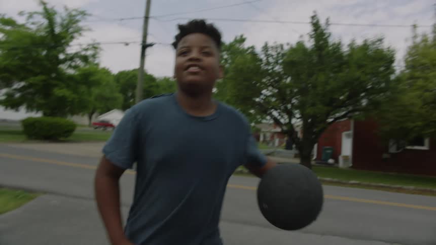 A boy catches a basketball dribbles and shoots it as he plays in his driveway