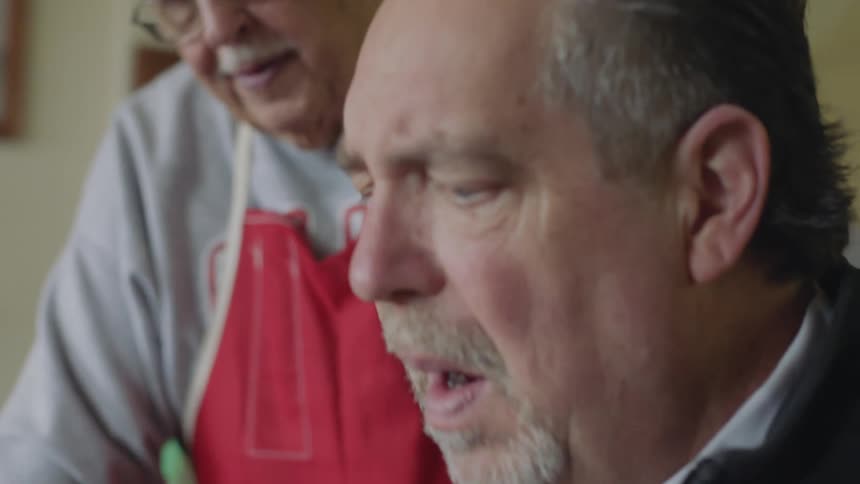 Two elderly men talk examine something together