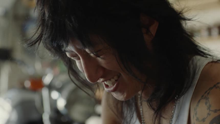 A young asian man is looking down as he talks and laughs