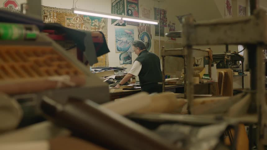 A man walks across a shop and picks up a picture frame and walks away with it