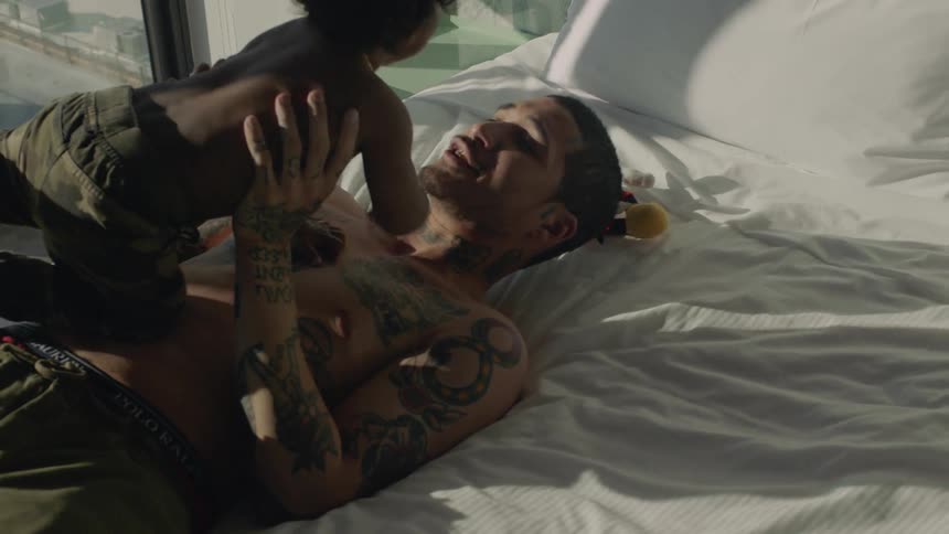 Father lies on bed playing with son