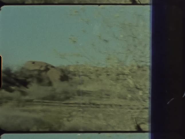 A rock formation sits behind a pole in a field