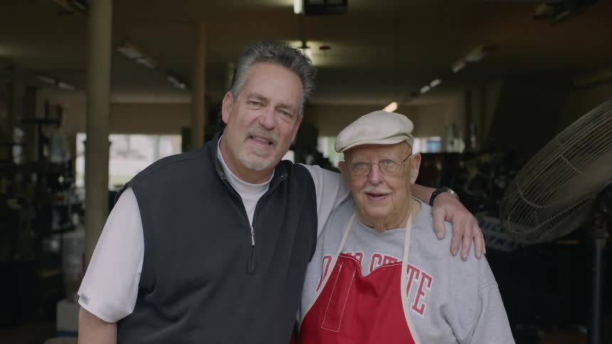 Two men are smiling and posing for a picture