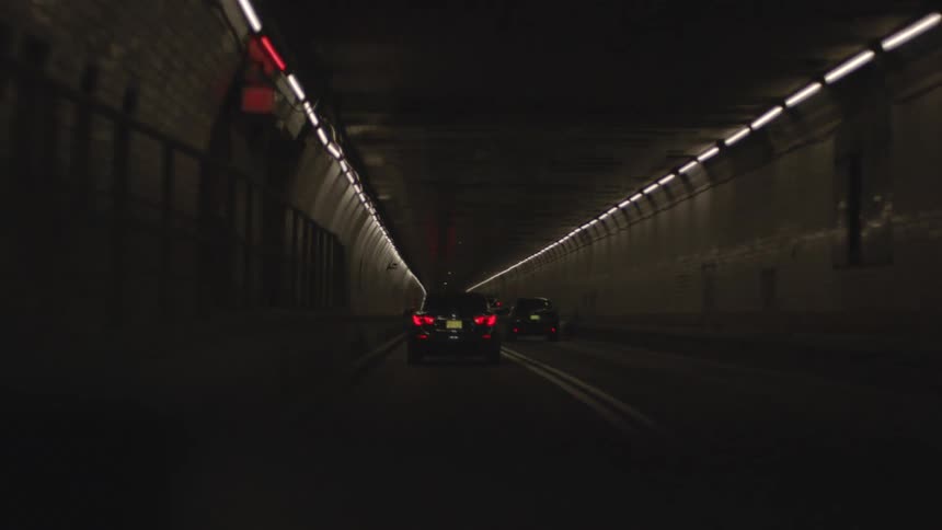 A vehicle is moving through a very dark and curving tunnel