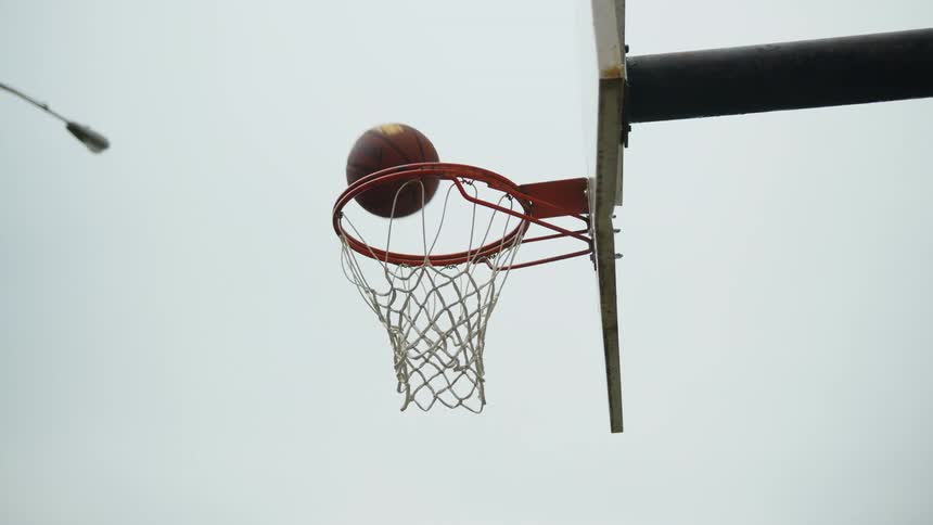A man shoots a layup scoring a basket in an outdoor hoop