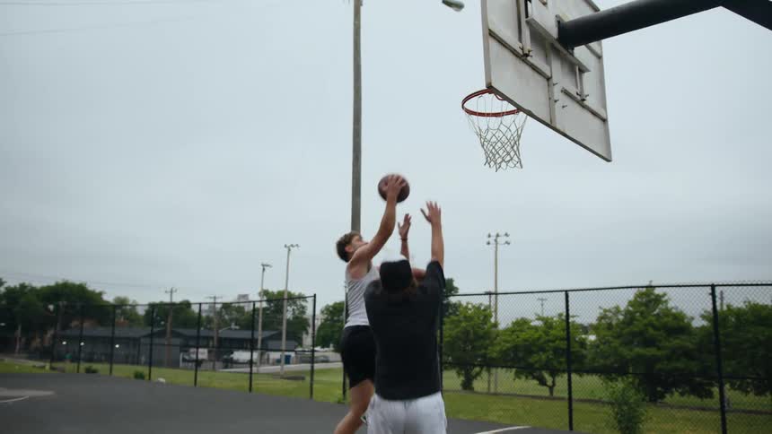 Two men playing basketball together in a park