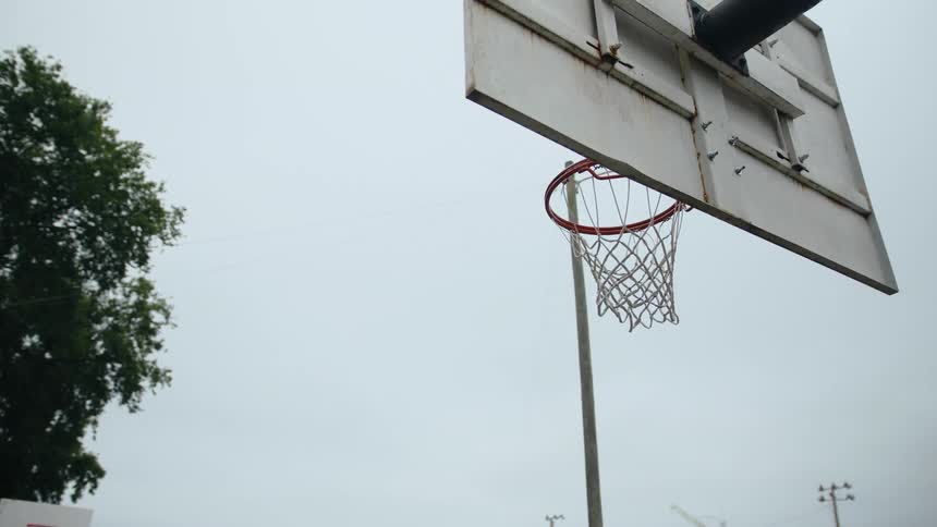 A man jumps with a basketball to the hoop and the ball drops through the net
