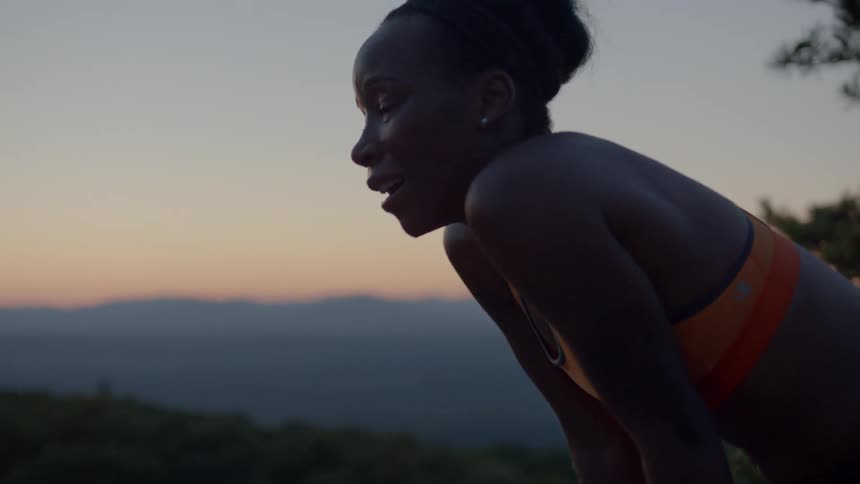 A woman rests after running at dusk