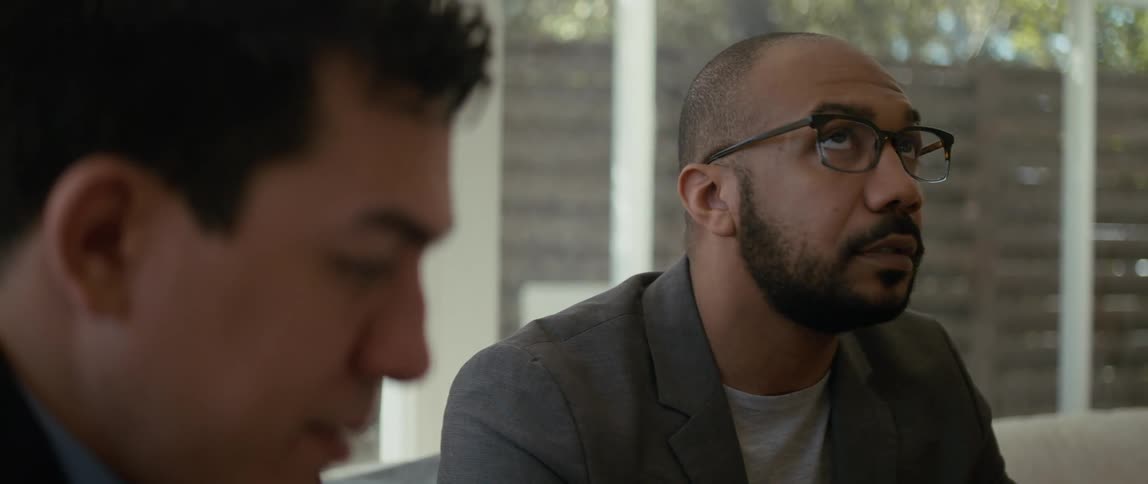 Two men are sitting outside and looking around