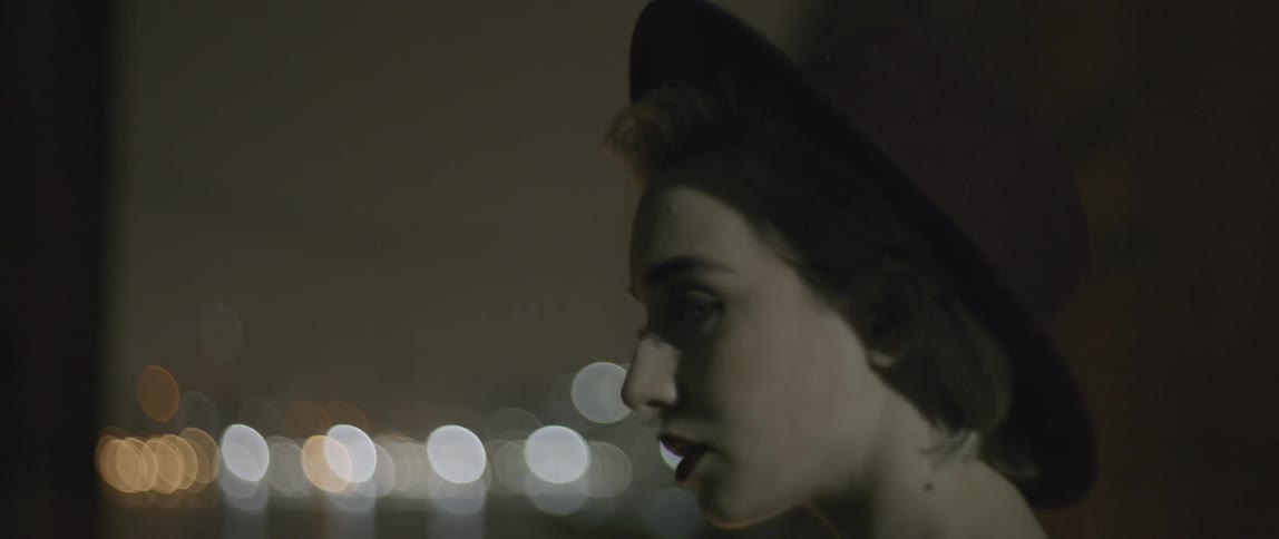 A woman turning away from the city skyline near the water