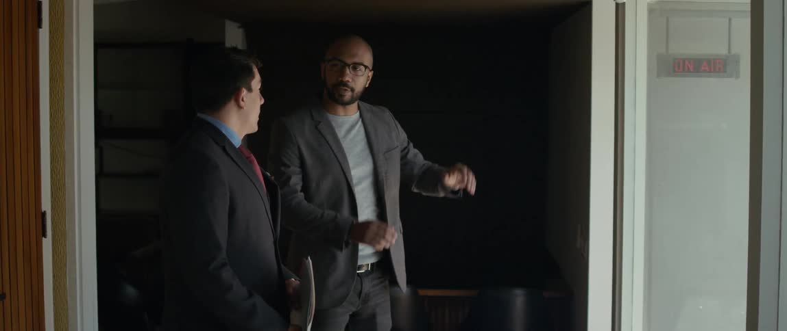 Two men are standing together and one man is using his hands as he talks