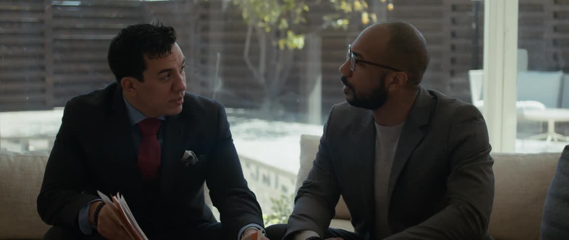 Two colleagues discuss paperwork in an open courtyard