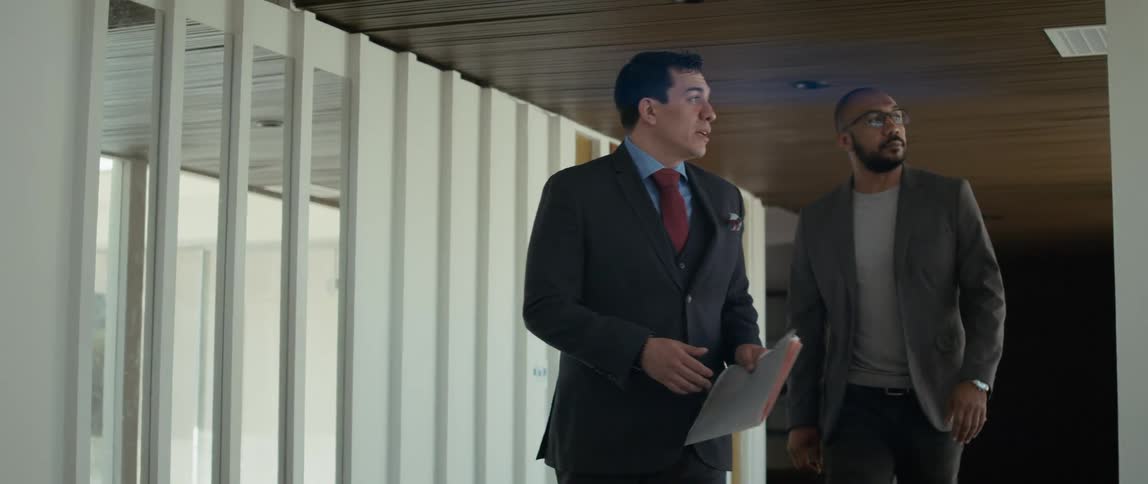 A realtor holding a folder talks to a client as they walk through a property