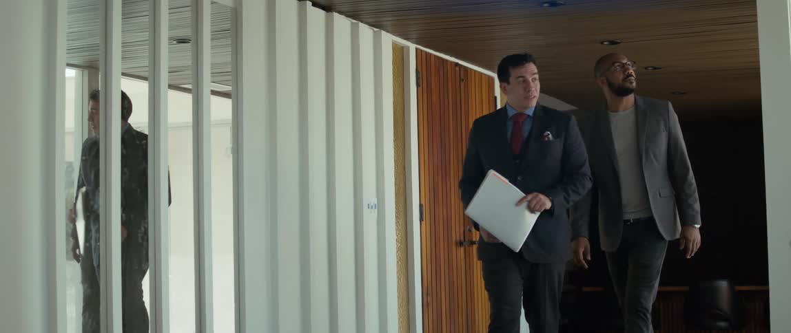 A man carrying a folder walks next to his client talking and indicating different points