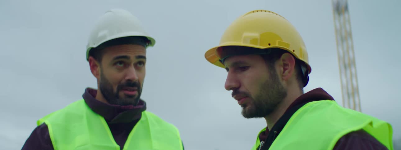 Two construction workers talk on site