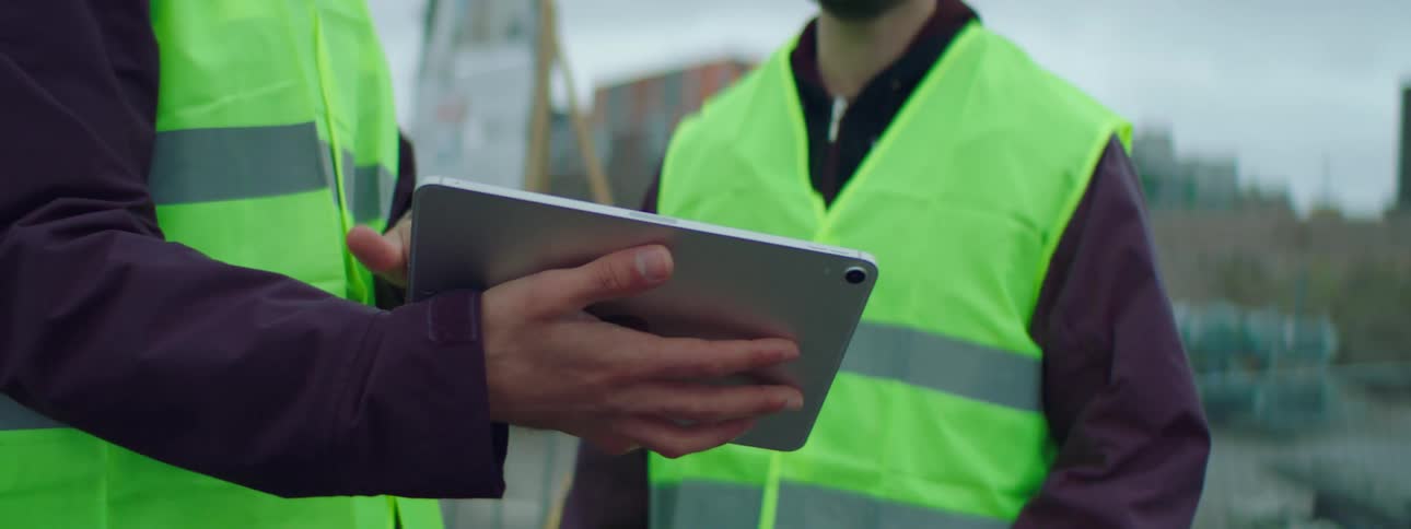 Two construction workers look at a tablet together