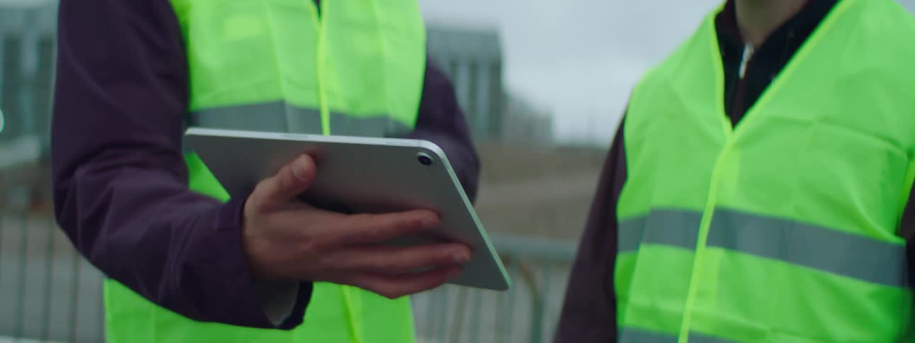 Closeup of two construction workers using a tablet on a construction site