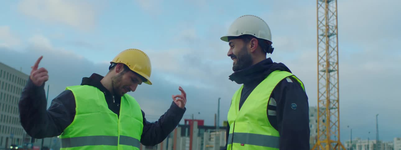 Two construction workers hanging out and laughing at a job site