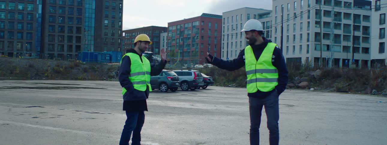 Construction workers give each other a fist bump before leaving a site