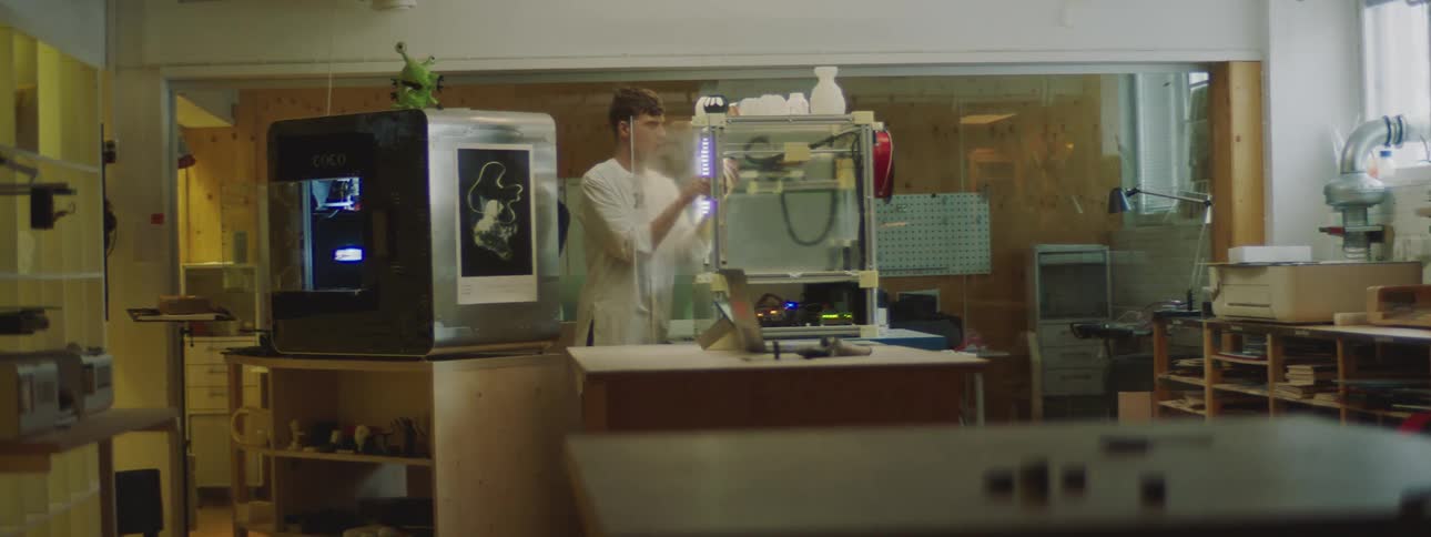 A man gets up from his seat and opens the door to a 3d printer