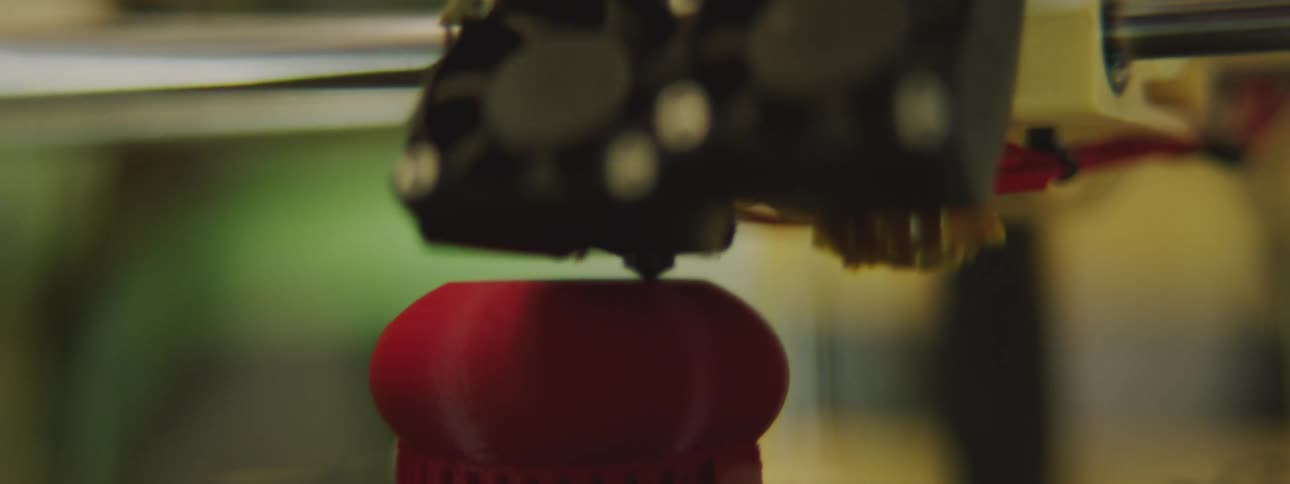 A small round red object is printed with a three dimensional printer