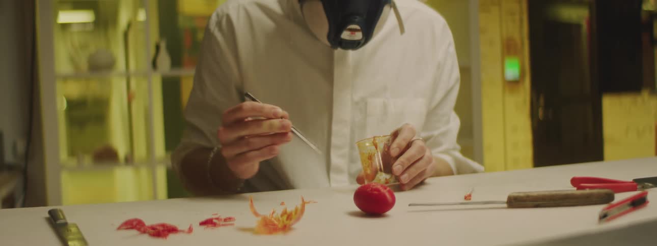 A man in a factory pulls dried up material out of a beaker