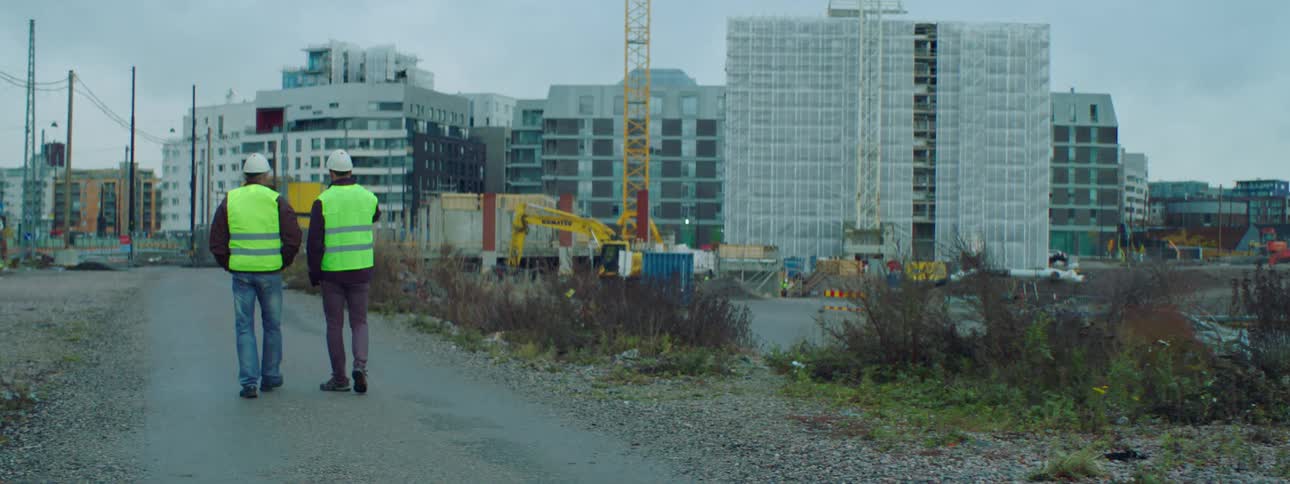 Two construction workers chat as they walk through a site
