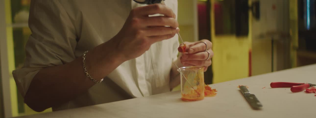 A woman adding ingredients to a beaker in a science lab