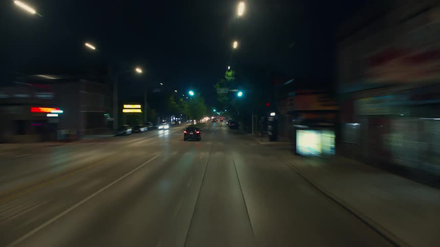 Lights shine in the darkness as traffic moves on a city street at night