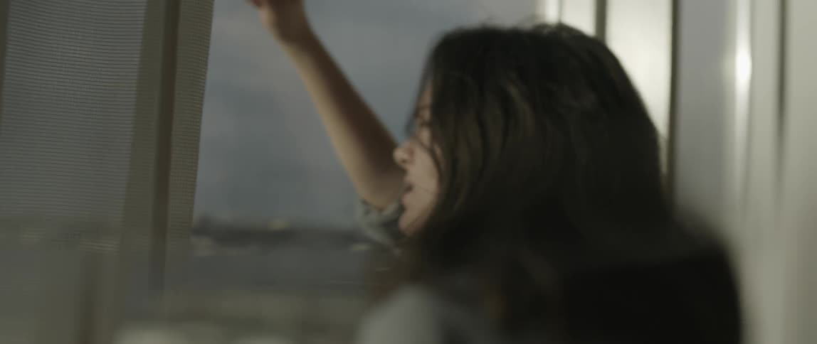 A woman is upset and leans against a window