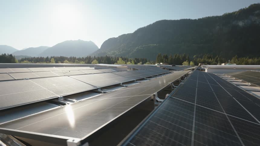 Panning shot of solar panels next to a nature backdrop