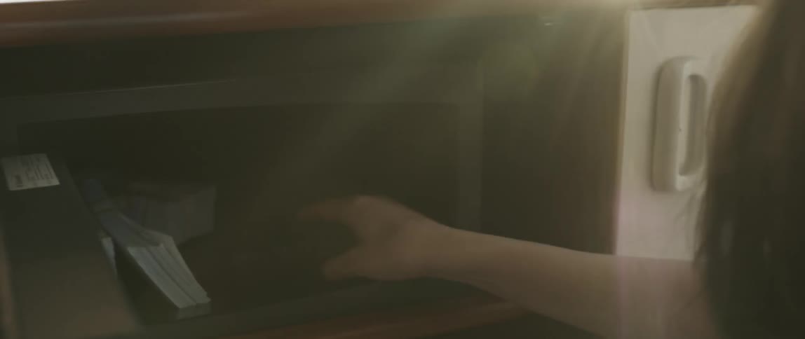 A woman grabs money and a gun from a safe