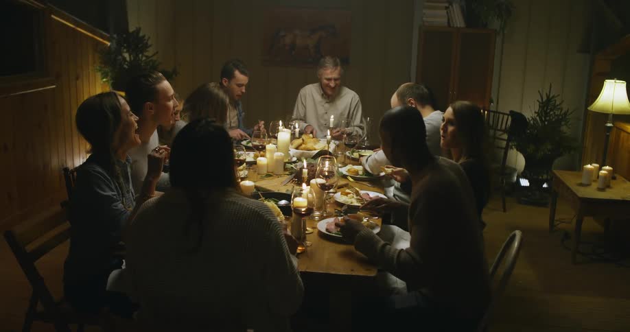 Family having a dinner at a large candlelit dining table