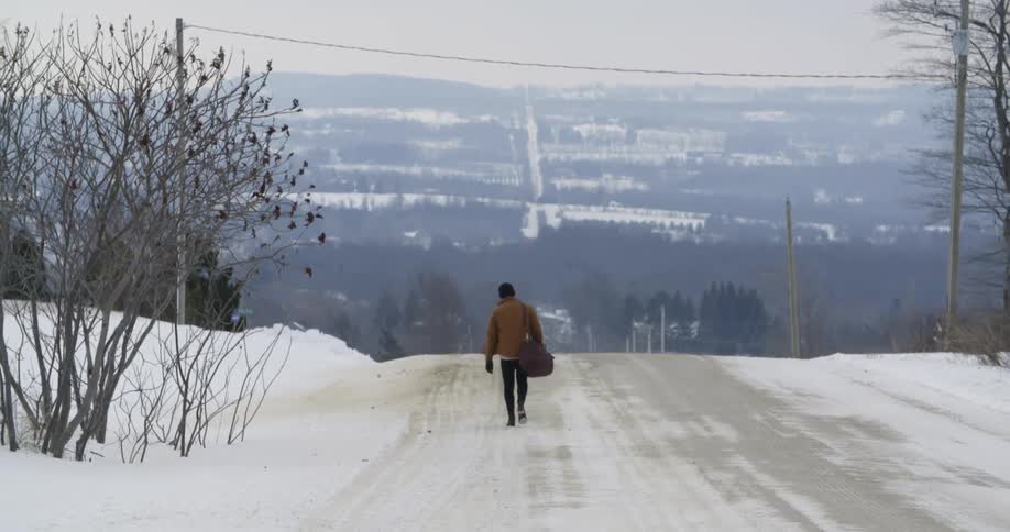 Man is walking down a snow covered road