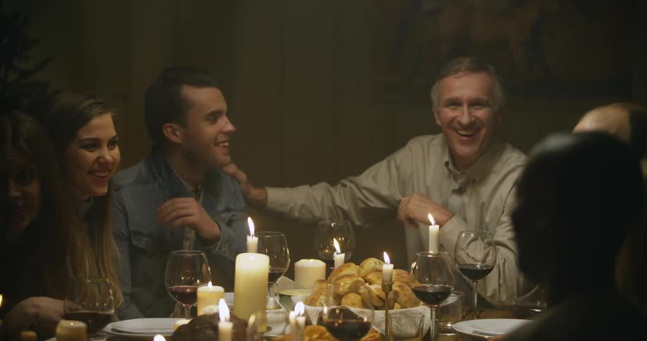 A smiling man pats another man on the back at the dinner table
