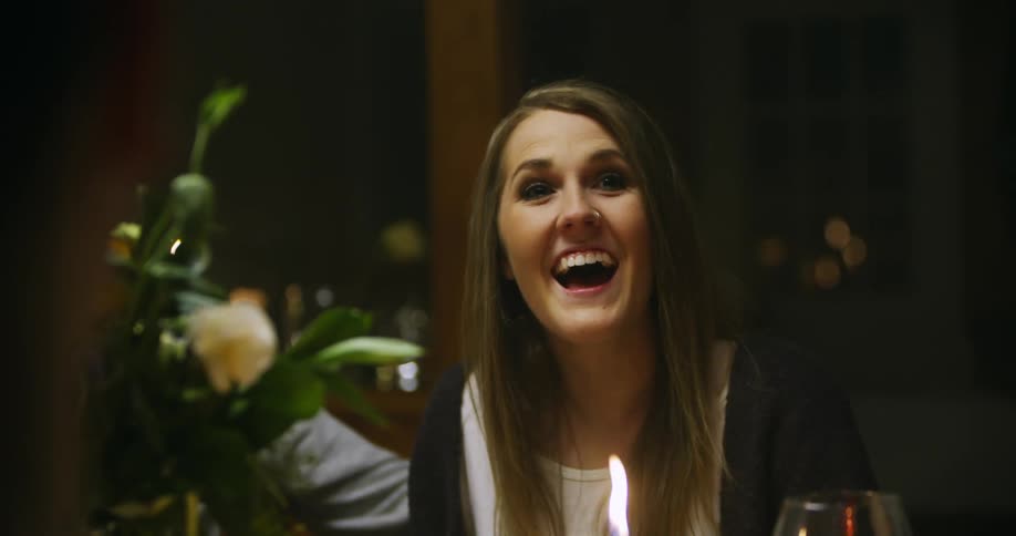 A woman smiles as she sits at a table with others