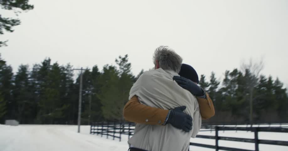 Two men run towards each other outside and embrace