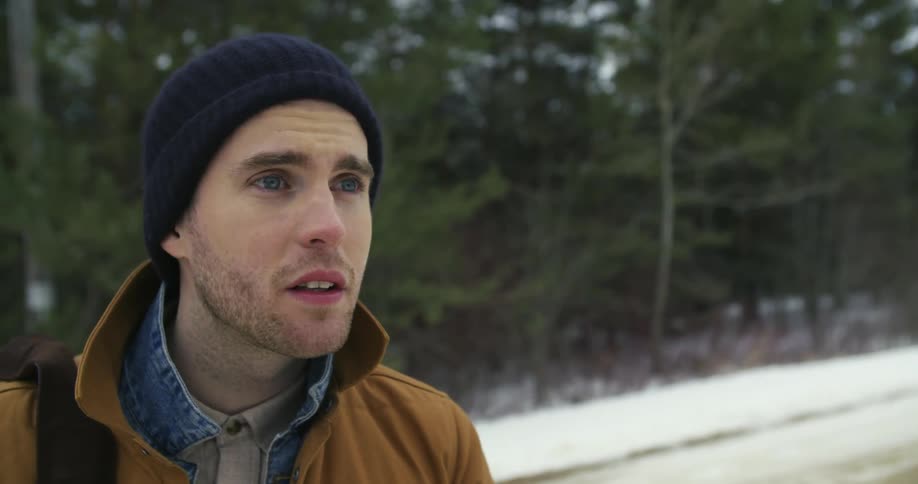 A man in a black beanie raises his eyebrows and walks away