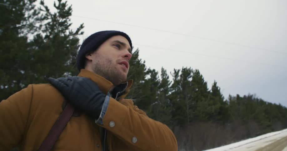 A man is walking outside along a snow filled road