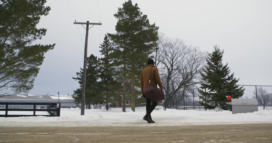 A man stops on a snow covered road