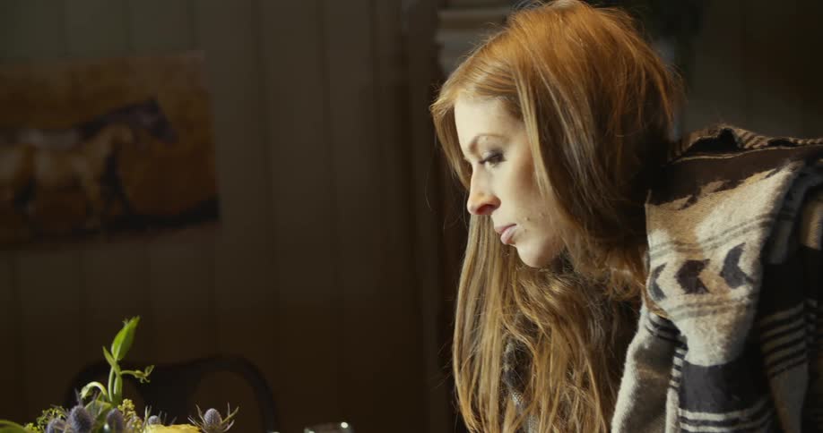 A woman placing a flower arrangement on a table