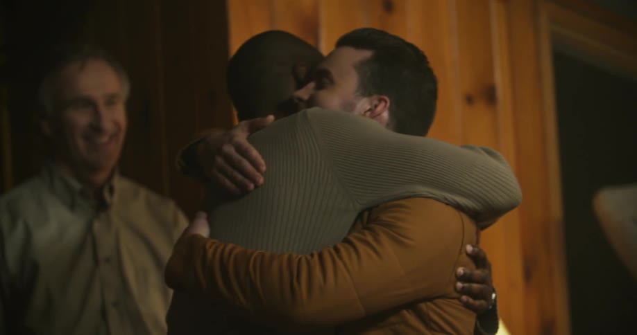Two men hug while people watch